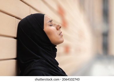 Desperate Young Muslim Woman In Hijab Leaning On Concrete Wall Outdoors, Side View Shot Of Depressed Millennial Islamic Lady Wearing Headscarf Standing With Closed Eyes, Suffering Problems, Closeup