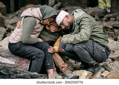 Despondent Arabian family sitting on ruins of house and hugging each other after hostilities, war concept