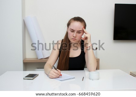 Despondent businesswoman sitting at her desk resting her head in her hand covering her eyes