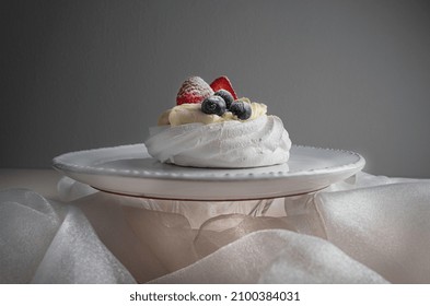 Dessert Anna Pavlova with strawberry and blueberry on a white plate with decorations.
