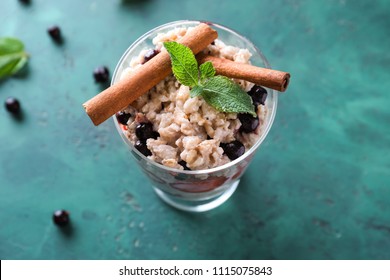 Dessert bowl with tasty oatmeal, berries and cinnamon sticks on color textured background - Powered by Shutterstock