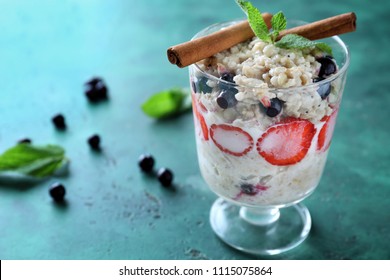 Dessert bowl with tasty oatmeal, berries and cinnamon sticks on color textured background - Powered by Shutterstock