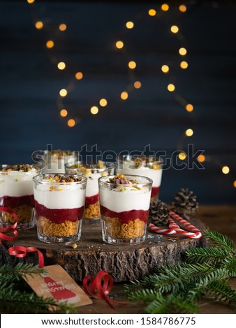 Dessert in a glasses with chocolate and berries spread on wooden background with garland lights bokeh and christmas decoration. Christmas, new year holidays background concept. Dessert recipe ideas.