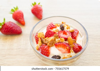 A Dessert Made Of Greek Yougurt, Granola And Fresh Red Strawberries In Compositions With A Spoon And Space In A Wood Background