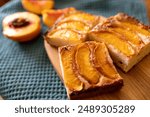 A dessert made of sliced peaches is on a wooden cutting board. The dessert is covered in sugar and looks delicious.