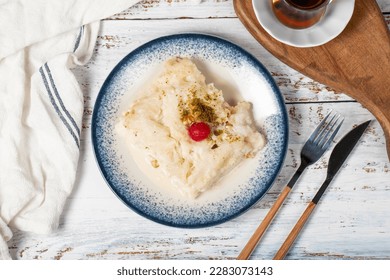 Güllaç dessert on wood background. Traditional Ramadan dessert. Güllaç dessert topped with sour cherry and pistachio. Top view - Shutterstock ID 2283073143