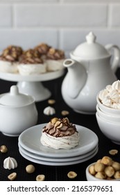 Dessert Pavlova with chocolate and hazelnuts. There is a dessert and white dishes on the table, a light background. Cream with mascarpone and whipped cream.