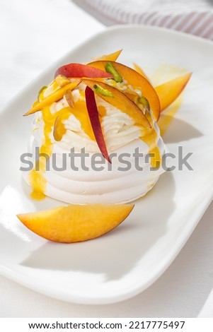 Dessert Pavlova of meringue with passion fruit, nectarines and pistachio on white background for restaurant menu.