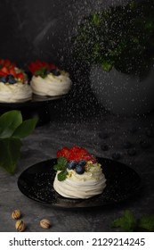 Dessert Pavlova with strawberries, blueberries and pistachios. Cream cheese cream - mascarpone and berries. Meringue for Pavlova dessert. Dessert on a dark background.