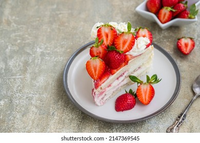 Dessert, sliced sponge cake with custard, fresh strawberries and whipped cream on a gray concrete background. Swedish cuisine. Strawberry recipes