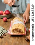 Dessert, sponge roll with apple filling, on a rectangular plate on a brown wooden background. Apple recipes. Thanksgiving Day