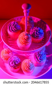 Dessert stand with tasty cupcakes on dark color background, closeup