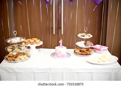 dessert table at one year old birthday party with cakes and assorted pastries - Powered by Shutterstock