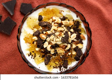 Dessert Yogurt Bowl With Orange Marmalade, Dark Chocolate And Hazelnuts On Red Background, Top Down View