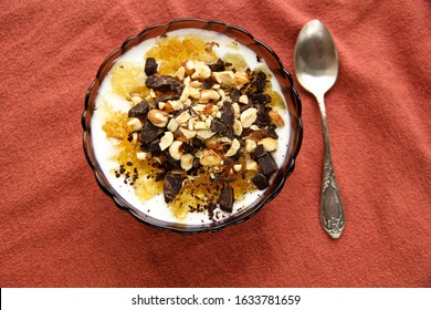 Dessert Yogurt Bowl With Orange Marmalade, Dark Chocolate And Hazelnuts On Red Background, Top Down View