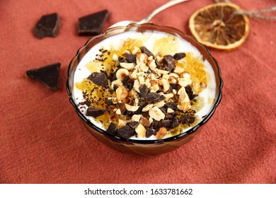 Dessert Yogurt Bowl With Orange Marmalade, Dark Chocolate And Hazelnuts On Red Background, Top Down View