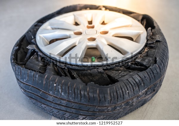 Destroyed\
blown out tire with exploded, shredded and damaged rubber on a\
modern suv automobile. Flat low profile tyre on an alloy rim,\
ripped open in pieces with visible\
interior.