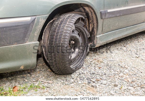 Destroyed blown out\
tire with exploded, shredded and damaged tire on a modern\
automobile. damaged truck rubber after tire explosion at high\
speed. Damaged flat tires: old\
car.