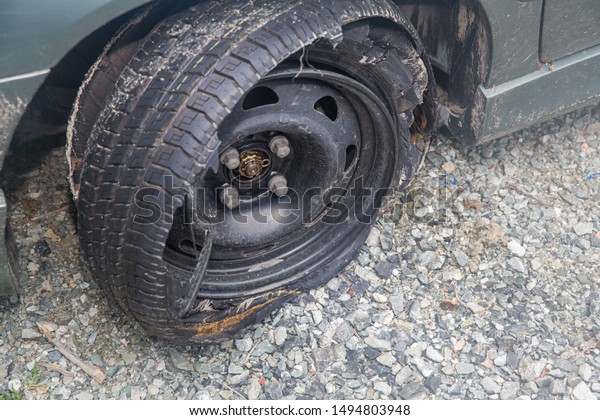 Destroyed blown out\
tire with exploded, shredded and damaged tire on a modern\
automobile. damaged truck rubber after tire explosion at high\
speed. Damaged flat tires: old\
car.