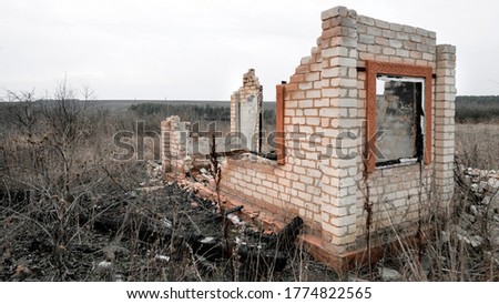 Destroyed and burnt brick structure with a window at the edge of the field. Scattered garbage, an atmosphere of despondency and desolation.