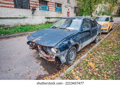 Destroyed Car On The Dirty Suburbian Street.