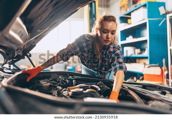 Destroying\
gender stereotypes. Young woman auto mechanic working at auto\
service station using different work tools. Gender equality. Work,\
occupation, car. Pretty girl in work\
clothes
