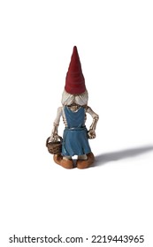 Detail Back Shot Of A Designer Figurine Of A Skeleton Of A Dwarf Woman In A Red Hat And A Blue Dress With A Basket In Hand. The Original Handmade Statuette Is Isolated On The White Background.        