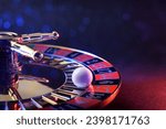 Detail of ball fixed on the black six of a casino roulette wheel on table and dark isolated background with soft red and blue lighting in the dark.