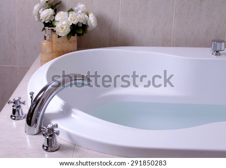 detail of bathroom, white bath tub with faucet and beige tiles, selective focus