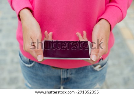 Detail of a beautiful young woman holding a phone in his hand.
