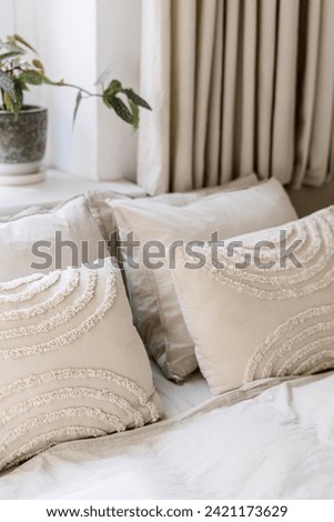 Detail in bedroom with scandinavian interior, decorative pillows on comfort bed with bedding linen. Soft textile in cozy room. Rest concept. Hotel with modern decor element and light tones design
