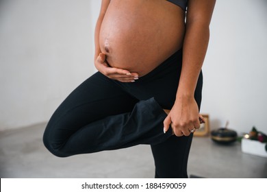 Detail of a belly of a pregnant mom during yoga exercises at home waiting for the birth of her daughter - Concept of life and love
