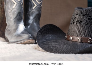 detail of black cowboy hat with blue boots on background