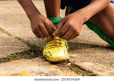 Detail of a black Latino boy tying his sports shoes on the asphalt in Neiva - Huila - Colombia - Powered by Shutterstock