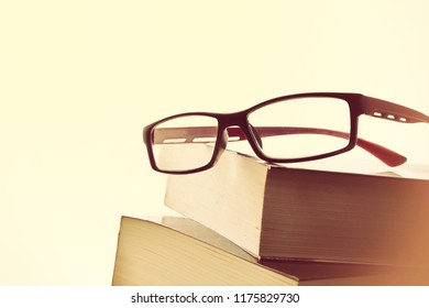 Detail of black and red reading glasses on two books vintage. Concept need glasses to read. Front view. Horizontal composition