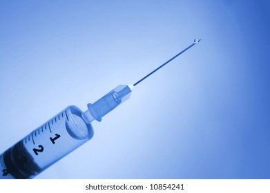 Detail einer blauen sterilisierten Spritze mit einem Arzneimitteltropfen auf der Nadel. Selektive Fokustiefe, um den Absturz zu betonen