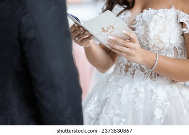 Detail of bridal gown with brides hands reading her vows on her wedding day
