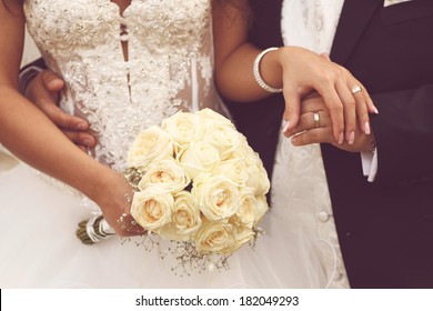 Detail of bride's roses bouquet and hands holding