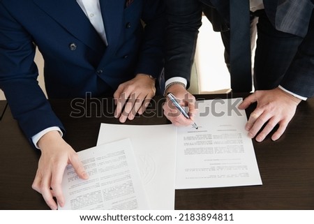 Detail of business meeting - signature licences, detail of hands, Close up business man reaching out sheet with contract agreement proposing to sign.Full and accurate details, 