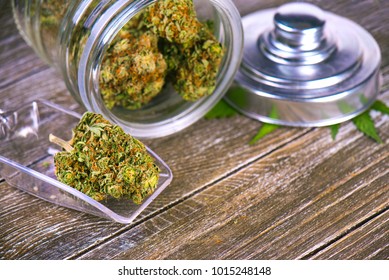 Detail of cannabis buds (scout master strain) on glass jar over wood background - medical marijuana dispensary concept