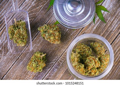 Detail of cannabis buds (scout master strain) on glass jar over wood background - medical marijuana dispensary concept