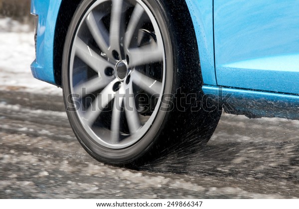 Detail of a car tire driving and splashing on\
the snow.  Driving on a snowy\
road
