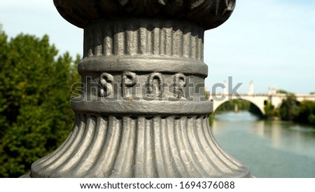 Detail of cast iron lamppost stand on a bridge with SPQR written (from the Latin Senatvs PopvlvsQve Romanvs) and blurred background on a sunny day. 
