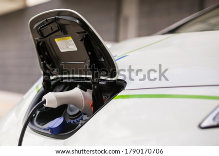 detail of a charging connector of a white electric car, while charging from a charging station