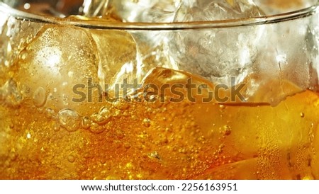 Detail of cider with ice cubes in glass. Extreme closeup, fresh beverages background.