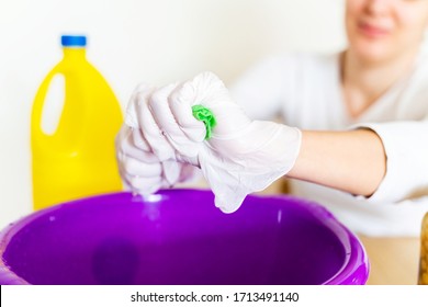 Detail of cleaning lady draining a wipe cloth with bleach in order to disinfect the house. Stay home concept and extreme hygiene protection against coronavirus covid-19 pandemic disease.