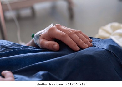 Detail close up photo of a patient´s hand with perfusion in it. Getting IV fluids. Ready for surgery after operation, in AR, emergency. Waiting. Symbolic photo, no faces, only hands. Intravenous drip