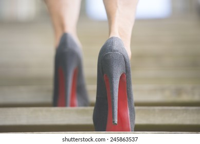 Detail Close Up Of Upward View Of Woman In High Heel Stiletto Shoes Walking Up Wooden Stairs With Blurred Background.