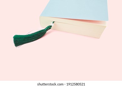 A Detail Of A Closed Book With A Bookmark, Isolated On Pink Background.