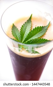 Detail of cold glass of beer with cannabis leaf  isolated over white, marijuana infused beverage concept